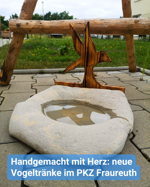 Eine Vogeltränke, gefüllt mit Wasser, in Betonoptik, mit einem geschnitzten Holzvogel obendrauf. Bildbeschriftung: Handgemacht mit Herz: neue Vogeltränke im PKZ Fraureuth