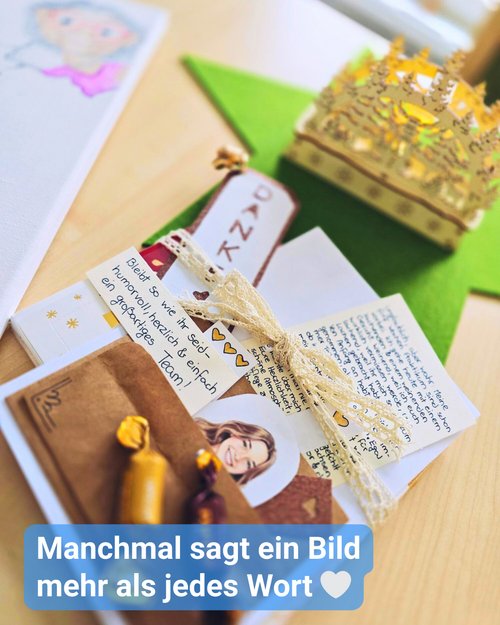 Ein liebevoll arrangiertes Abschiedsgeschenk liegt auf einem Tisch: handgeschriebene Karten, kleine Süßigkeiten, ein dekoratives Lesezeichen mit der Aufschrift „Danke“ und ein Portrait-Sticker der Praktikantin. Daneben steht eine filigrane, goldfarbene Papierkrone mit Licht. Die Szene vermittelt Wertschätzung und einen persönlichen Abschiedsmoment in der Tagespflege.