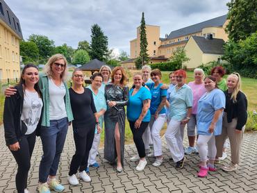 Eine Gruppe lachender Frauen, darunter eine Andrea Berg-Doppelgängerin, steht vor einem Gebäude.