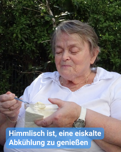 Eine ältere Frau genießt sichtlich ein Eis aus einem Becher im Freien. Text: 'Himmlisch ist, eine eiskalte Abkühlung zu genießen'.