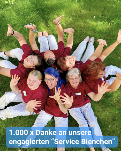 Sieben Frauen in Dienstkleidung vom Service sitzen im Kreis auf einer grünen Wiese - sie winken und lächeln in die Kamera. Bildbeschriftung: 1.000 x Danke an unsere engagierten “Service Bienchen”