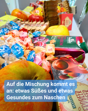 Ein großer Tisch ist gefüllt mit Süßigkeiten, Getränken sowie Obst. Bildbeschriftung: “Auf die Mischung kommt es an: etwas Süßes und etwas Gesundes zum Naschen”