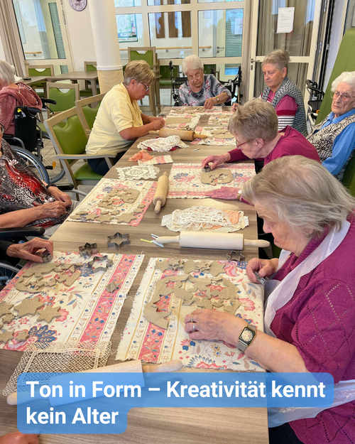 Seniorinnen und Senioren sitzen gemeinsam an einem großen Tisch und stechen Formen aus Ton aus. Bildbeschriftung: Ton in Form – Kreativität kennt kein Alter