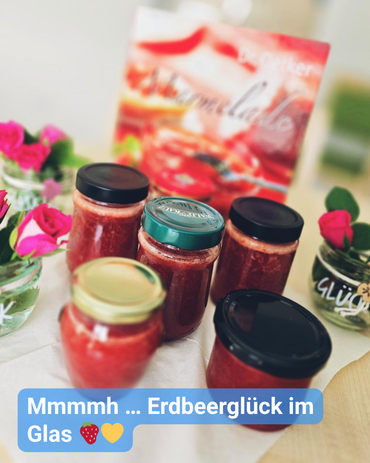 Mehrere Gläser mit roter Erdbeermarmelade auf einem Tisch. Text: 'Mmmmh ... Erdbeerglück im Glas'.