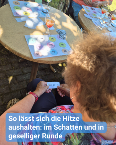 Menschen spielen ein Spiel mit nummerierten Kreisen, während sie im Schatten sitzen, um der Hitze zu entkommen.