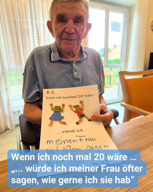 Ein älterer Herr sitzt an einem Holztisch, und er hält lächelnd ein Papier in die Kamera. Bildbeschriftung: Wenn ich noch mal 20 wäre … „... würde ich meiner Frau öfter sagen, wie gerne ich sie hab”