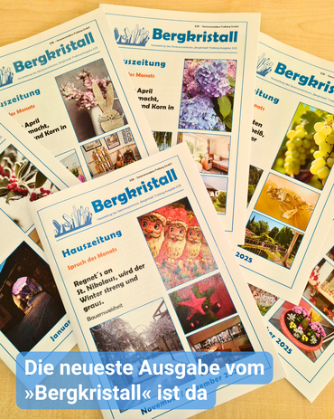 Auf einem Holztisch liegen verschiedene Ausgaben der Hauszeitung Bergkristall ausgebreitet. Bildbeschriftung: Die neueste Ausgabe vom »Bergkristall« ist da