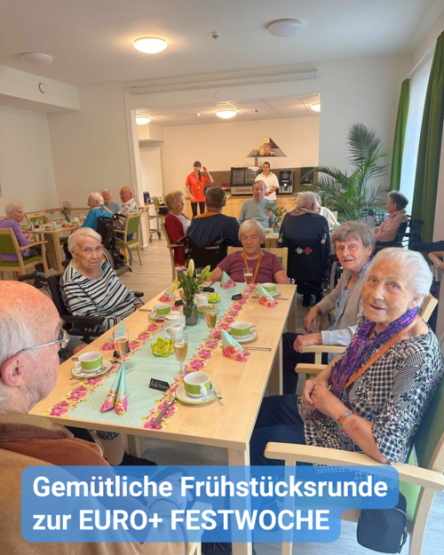 Bewohner sitzen an einem festlich gedeckten Tisch und frühstücken. Text: 'Gemütliche Frühstücksrunde zur EURO+ FESTWOCHE'.
