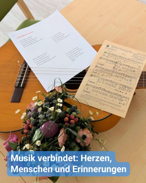 Eine Gitarre liegt auf einem Tisch, zusammen mit Notenblättern und Songtexten. Bildunterschrift: Musik verbindet: Herzen, Menschen und Erinnerungen