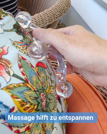 Eine Hand massiert mit einem durchsichtigen Massagegerät den Rücken einer Person. Text: 'Massage hilft zu entspannen'.