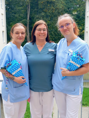 Eine Frau überreicht Zuckertüten an zwei Kolleginnen