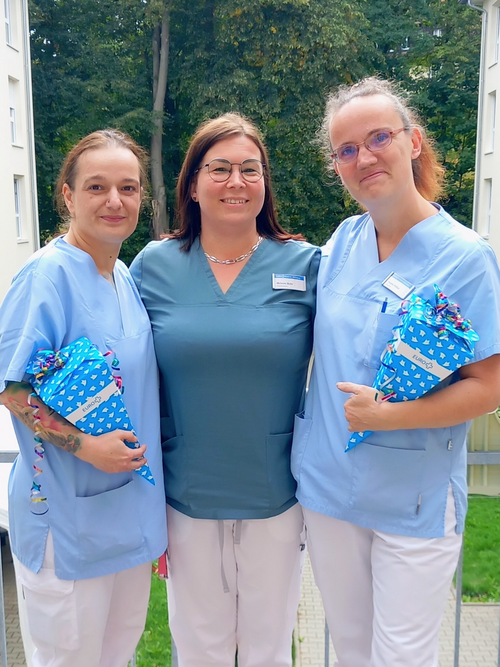 Eine Frau überreicht Zuckertüten an zwei Kolleginnen 