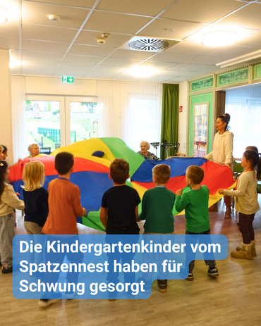 Kinder und Senioren machen gemeinsam gymnastische Übungen an einem Schwungtuch. Bildbeschriftung: Die Kindergartenkinder vom Spatzennest haben für Schwung gesorgt