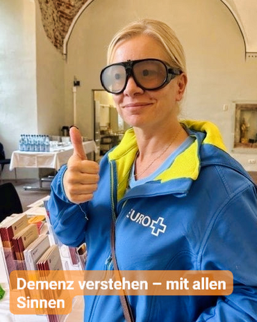 Frau trägt eine Brille, die altersbedingte Sehschwäche simuliert. Bildbeschriftung: Demenz verstehen - mit allen Sinnen