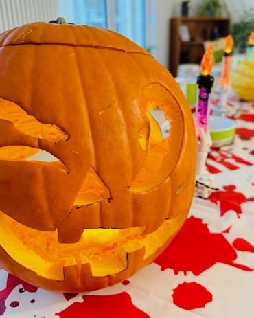 Halloween in der Tagespflege Fraureuth – liebevoll geschnitzter Kürbis mit leuchtendem Gesicht als Teil der herbstlichen Tischdekoration im Pflegekompetenzzentrum Fraureuth.